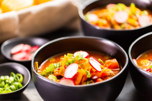 Turkey chili garnished with fresh radishes, green onions and cheddar cheese.