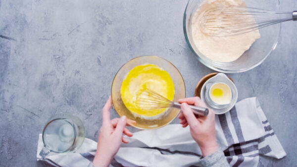 Step by step. Flat lay. Mixing ingredients together in glass mixing bowl for spicy jalapeno cornbread muffins.