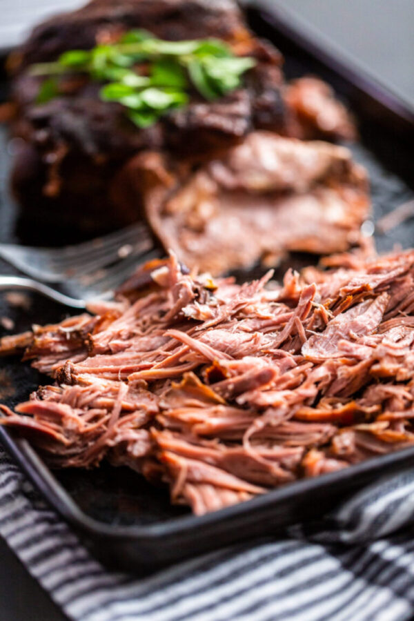 Shredded cooked pork with forks on a baking sheet.