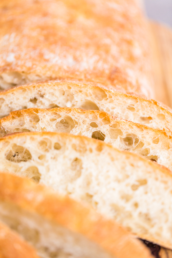 Sliced loaf of freshly baked ciabatta bread on gray table.