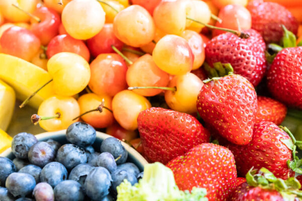 Snack board with fresh fruit, vegetables, crackers, and dips.