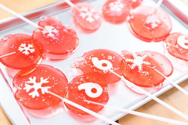 Homemade berry flavor lollipops with snowflakes on a white lollipop sticks.