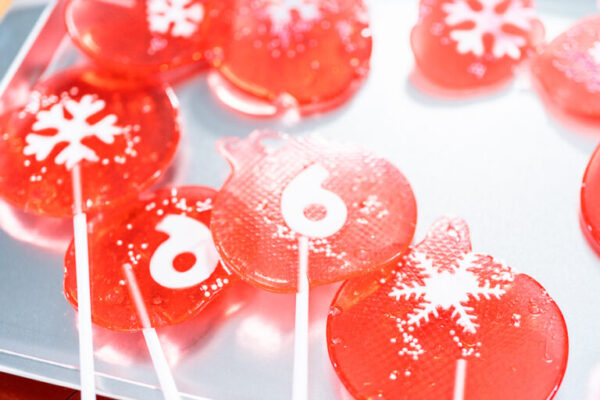 Homemade berry flavor lollipops with snowflakes on a white lollipop sticks.