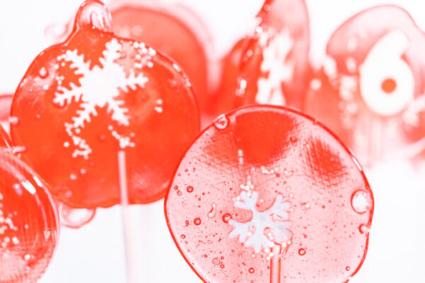 Homemade berry flavor lollipops with snowflakes on a white lollipop sticks.