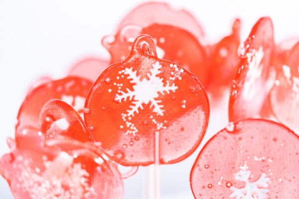Homemade berry flavor lollipops with snowflakes on a white lollipop sticks.