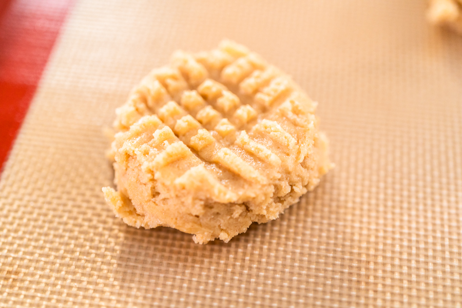 Cookie dough ball flattened with fork into traditional crisscross pattern