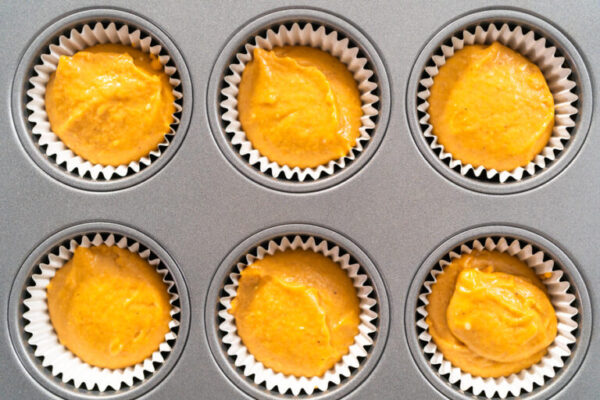 Pumpkin spice cupcake batter in a cupcake pan with liners.