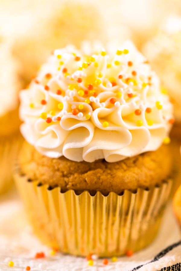Decorating pumpkin spice cupcake with Italian buttercream and sprinkles.