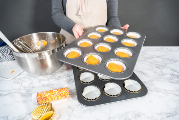 Pumpkin spice cupcake batter in a cupcake pan with liners.