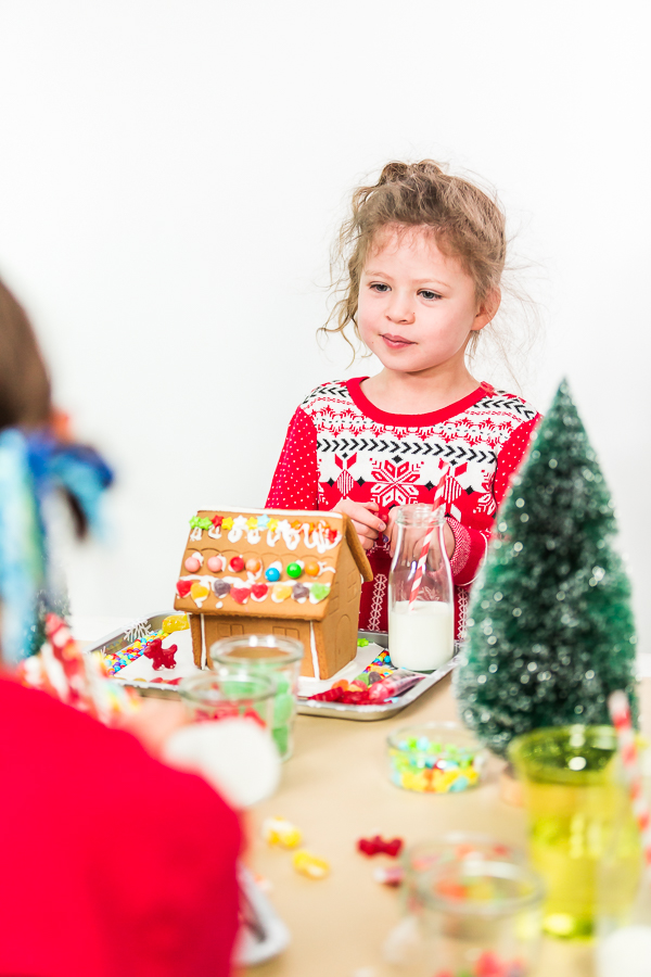Kids decorating small gingerbread houses at the Christmas craft party.