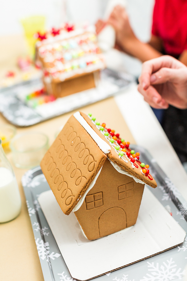 Kids decorating small gingerbread houses at the Christmas craft party.