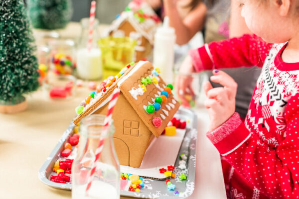 Kids decorating small gingerbread houses at the Christmas craft party.