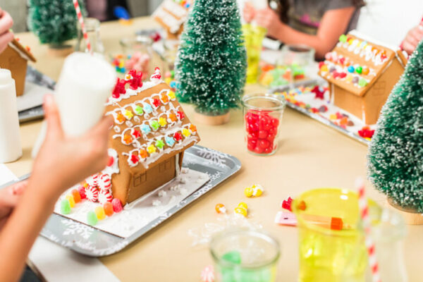 Kids decorating small gingerbread houses at the Christmas craft party.
