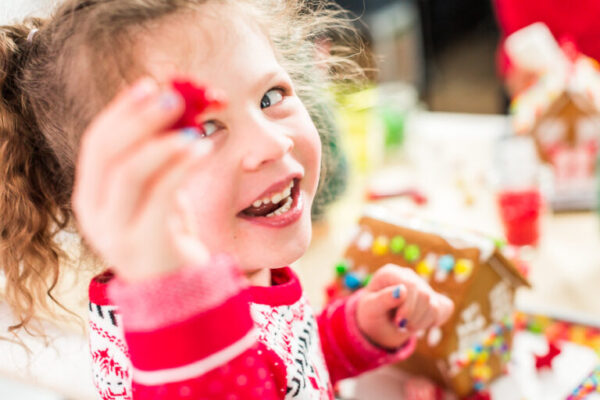 Kids decorating small gingerbread houses at the Christmas craft party.