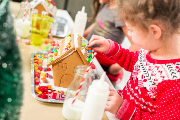 Kids decorating small gingerbread houses at the Christmas craft party.
