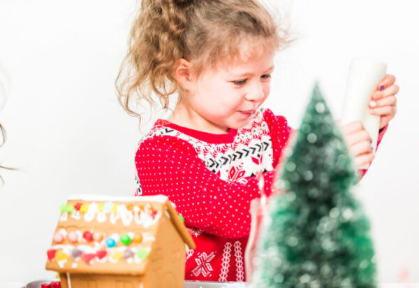 Kids decorating small gingerbread houses at the Christmas craft party.