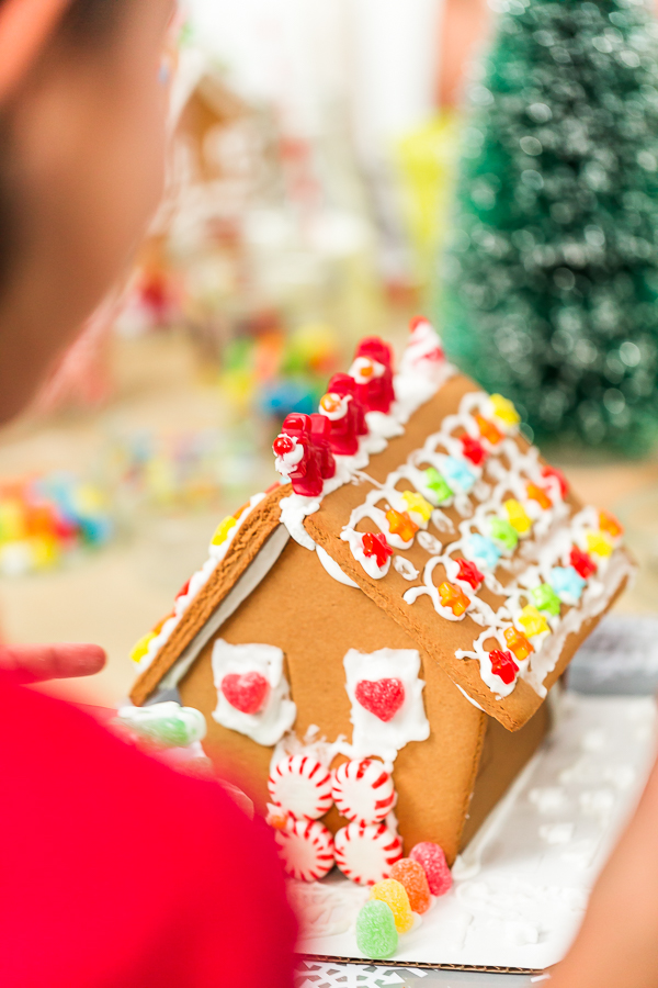 Kids decorating small gingerbread houses at the Christmas craft party.