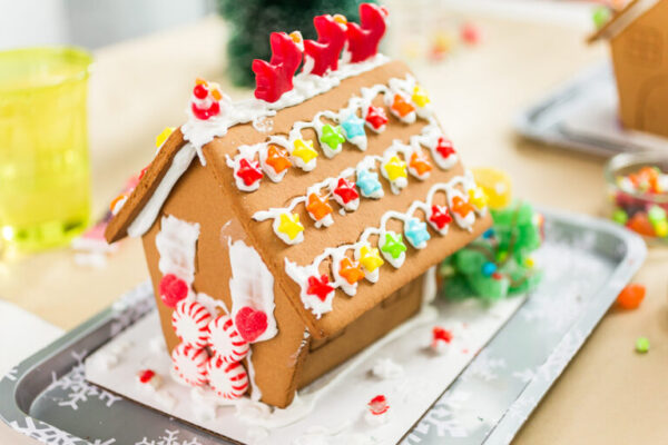 Kids decorating small gingerbread houses at the Christmas craft party.