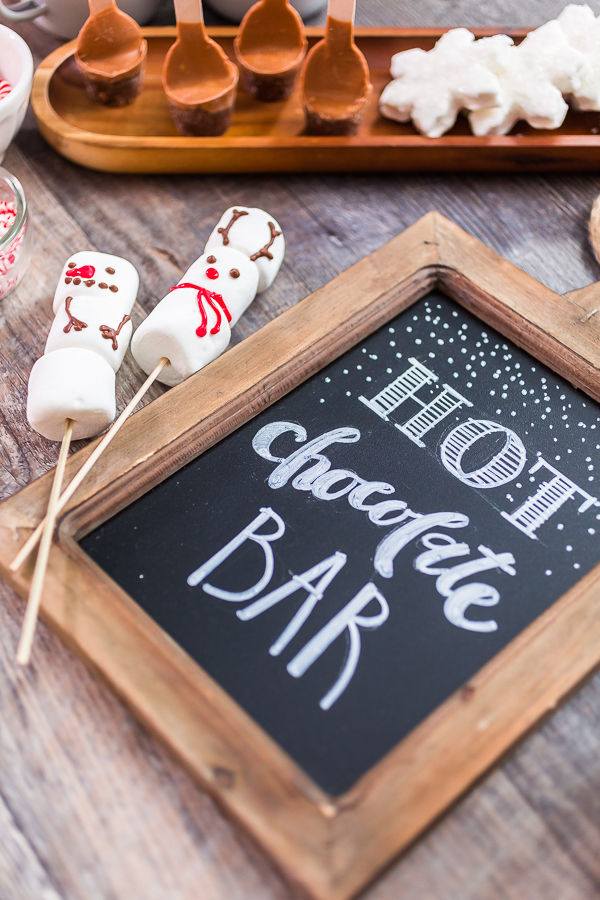 Chalk board with sign for hot chocolate bar with variety of topppings.
