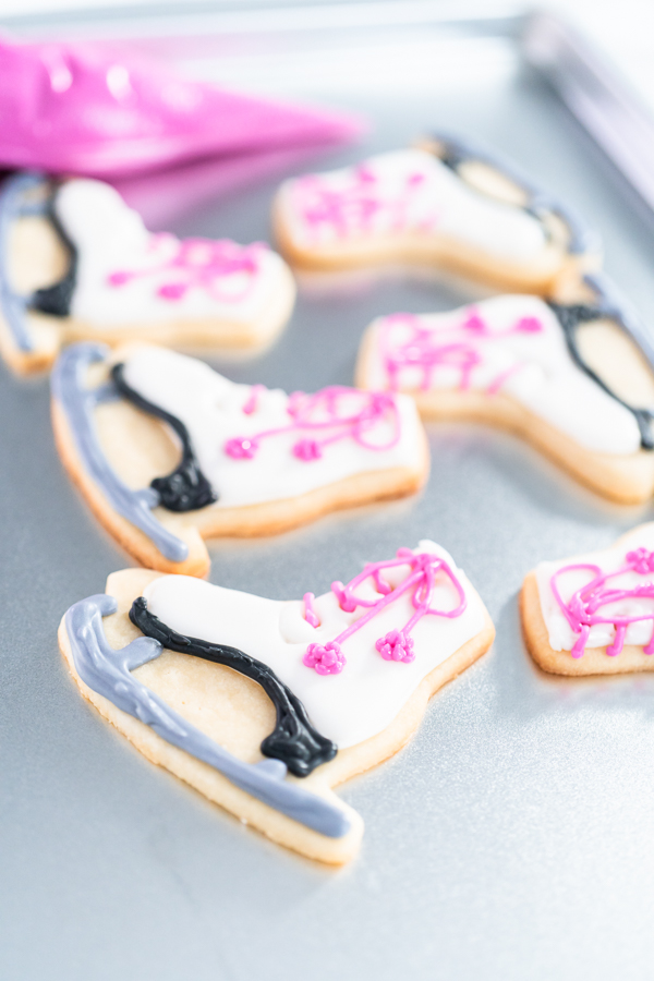 Decorating sugar cookies shaped as figure skates with royal icing.