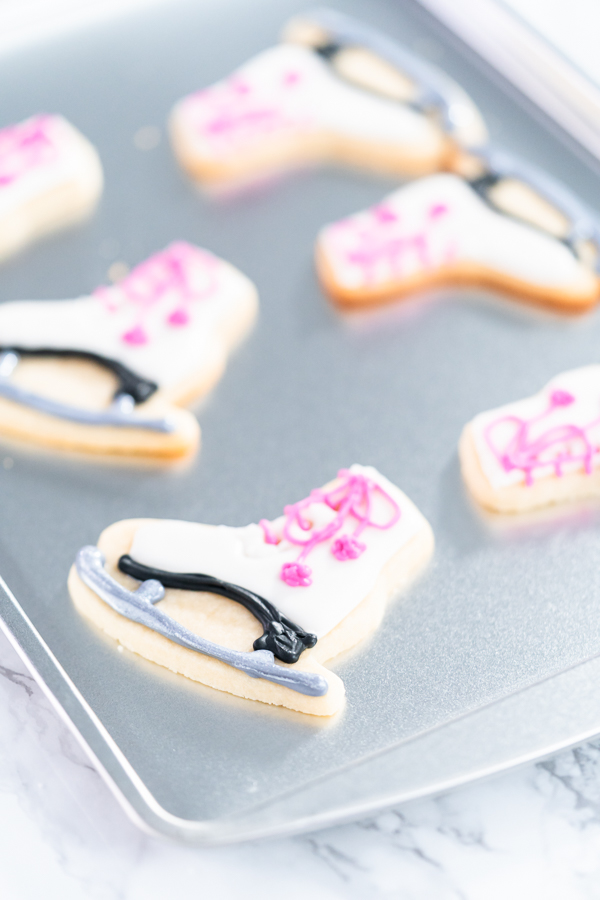 Decorating sugar cookies shaped as figure skates with royal icing.