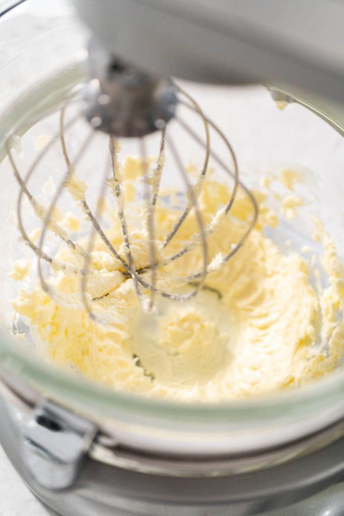 Softened butter being whipped in a stand mixer to begin the buttercream base.