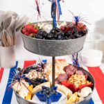 Full view of assembled vertical charcuterie board with festive ribbon and cocktail picks.