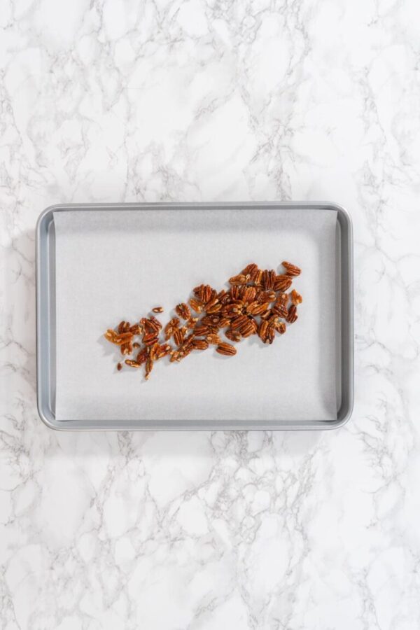 Spreading organic pecans on a baking sheet lined with parchment paper to make toasted pecans.