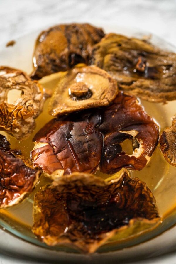 Soaking dehydrated wild mushrooms in a glass mixing bowl with hot water.