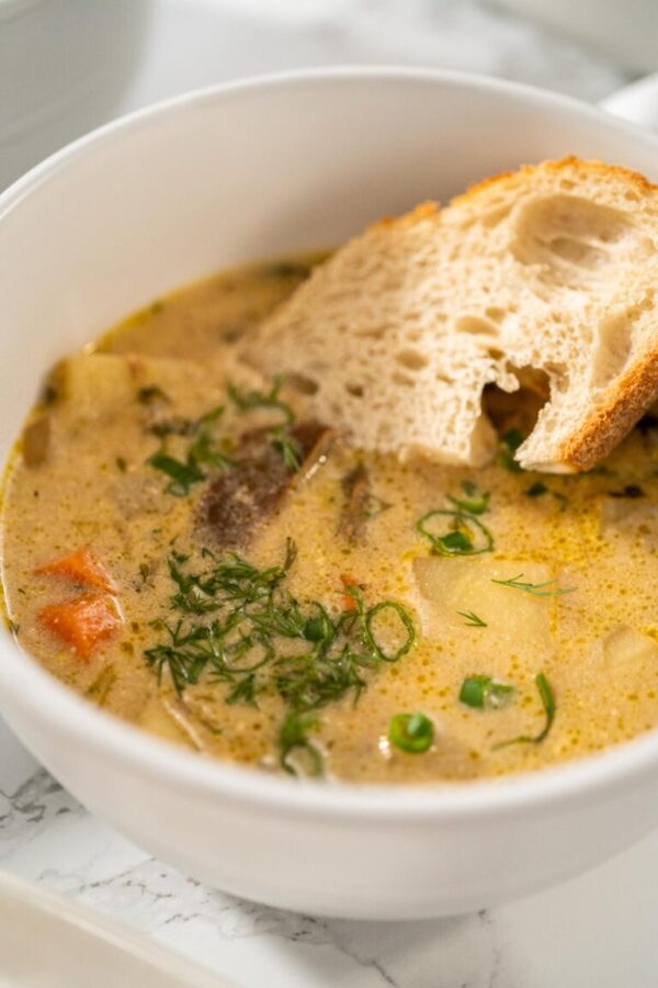 Serving creamy wild mushroom soup made out of dehydrated wild mushrooms in white bowls with sourdough bread.