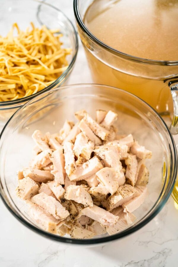 Measured ingredients in glass mixing bowls to make chicken noodle soup with kluski noodles.