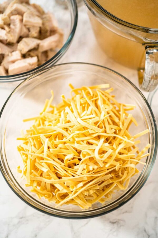 Measured ingredients in glass mixing bowls to make chicken noodle soup with kluski noodles.