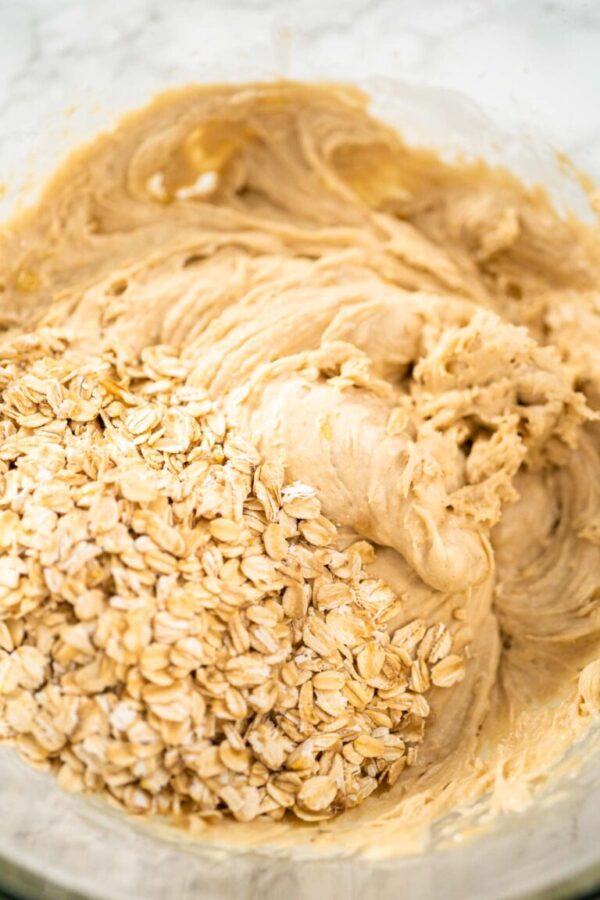 Mixing ingredients in a large glass mixing bowl to bake banana oatmeal muffins.