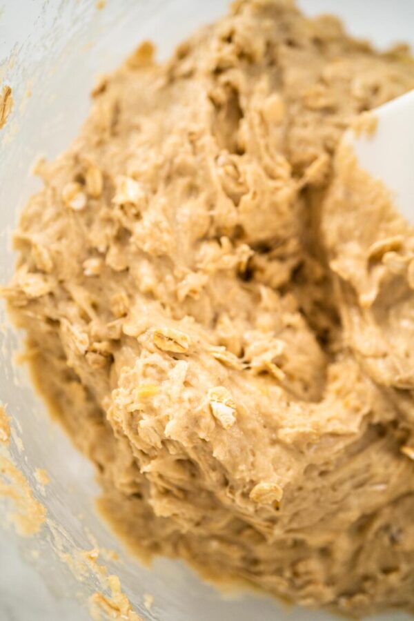 Mixing ingredients in a large glass mixing bowl to bake banana oatmeal muffins.