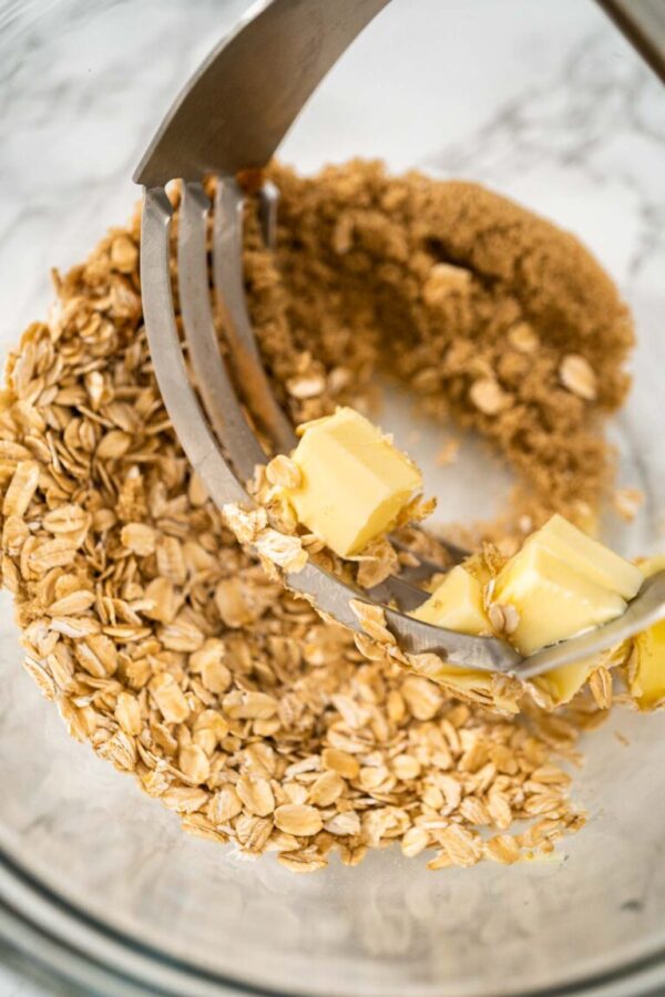 Mixing ingredients in a large glass mixing bowl to bake banana oatmeal muffins.
