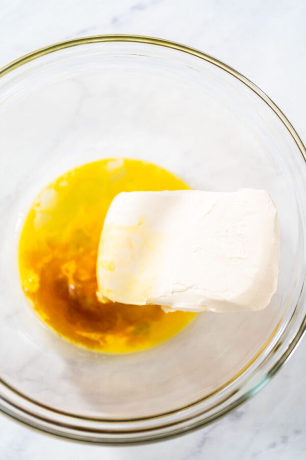 Mixing ingredients in a large glass mixing bowl to make the cream cheese filling for bundt cake.