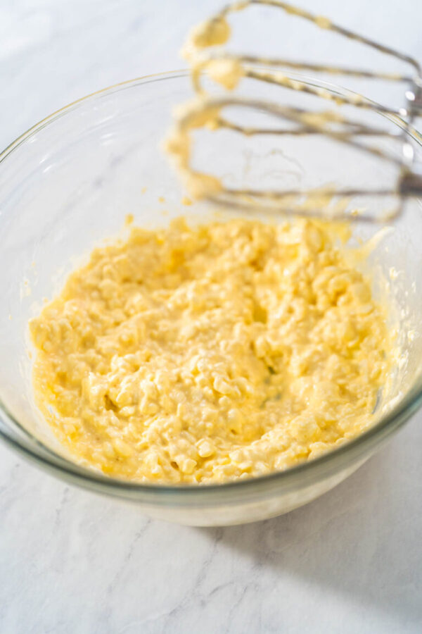 Mixing ingredients in a large glass mixing bowl to make the cream cheese filling for bundt cake.