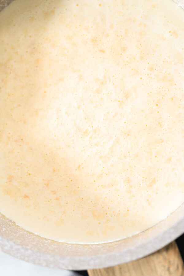 Heating whipped cream in a saucepan to make the white chocolate ganache frosting.