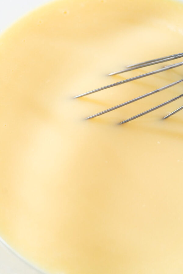 White chocolate ganache frosting - Arina Photography Whisking in a large glass bowl together ingredients to make the white chocolate ganache frosting.