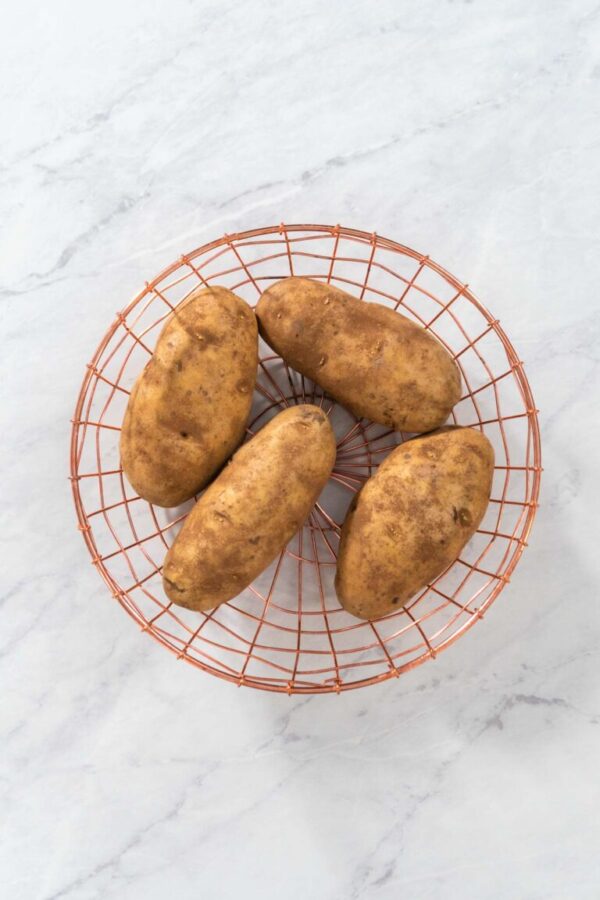 Flat lay. Pressure Cooker Baked Potatoes. Raw potatoes in a wire basket on the kitchen counter.