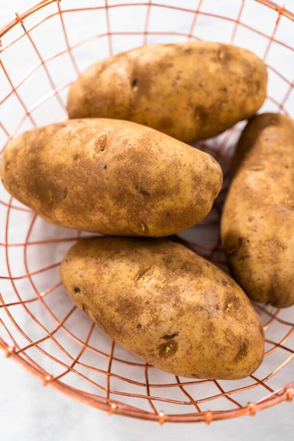 Pressure Cooker Baked Potatoes. Raw potatoes in a wire basket on the kitchen counter.