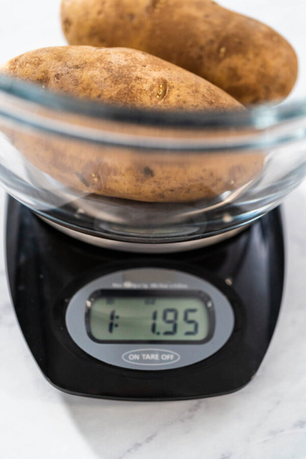 Pressure Cooker Baked Potatoes. Measuring raw potatoes in a glass mixing bowl on the kitchen scale.