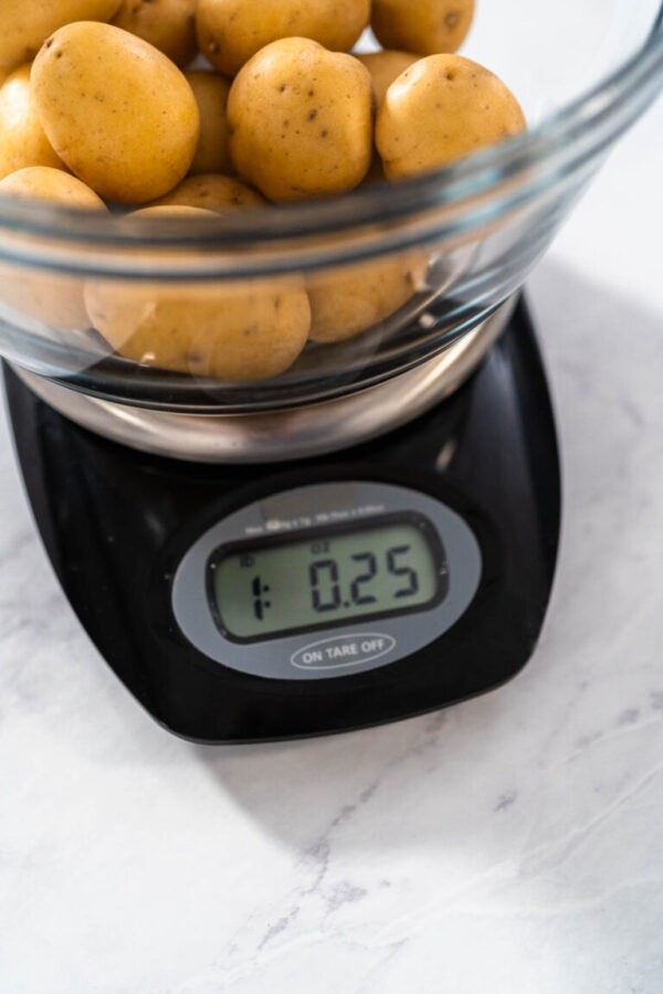 Pressure Cooker Baked Potatoes. Measuring raw potatoes in a glass mixing bowl on the kitchen scale.