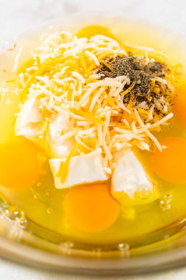 Mixing ingredients with a hand whisk in a glass mixing bowl to make egg bites.