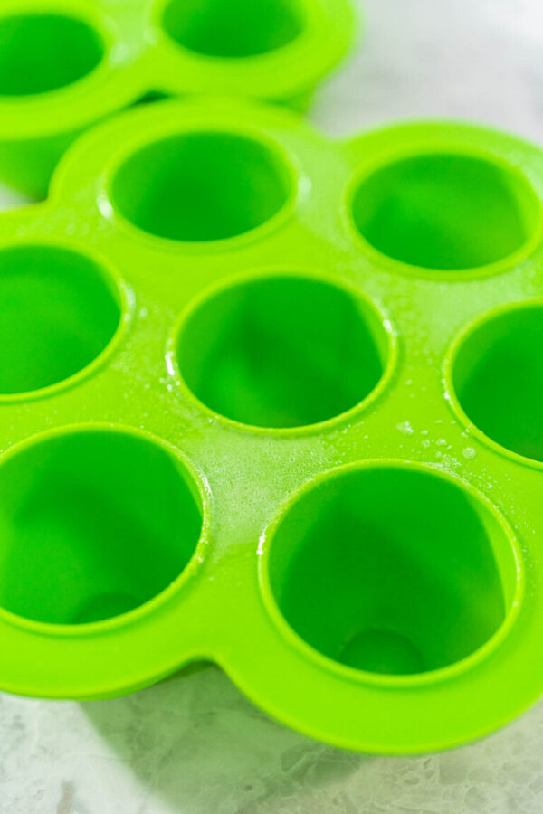 Filling silicone molds with egg mixture to make egg bites in a pressure cooker.