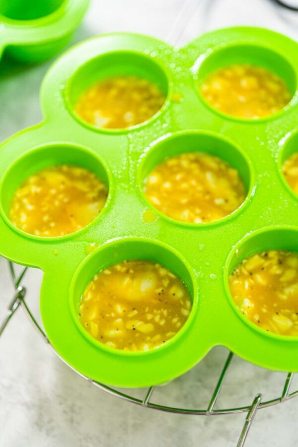 Filling silicone molds with egg mixture to make egg bites in a pressure cooker.