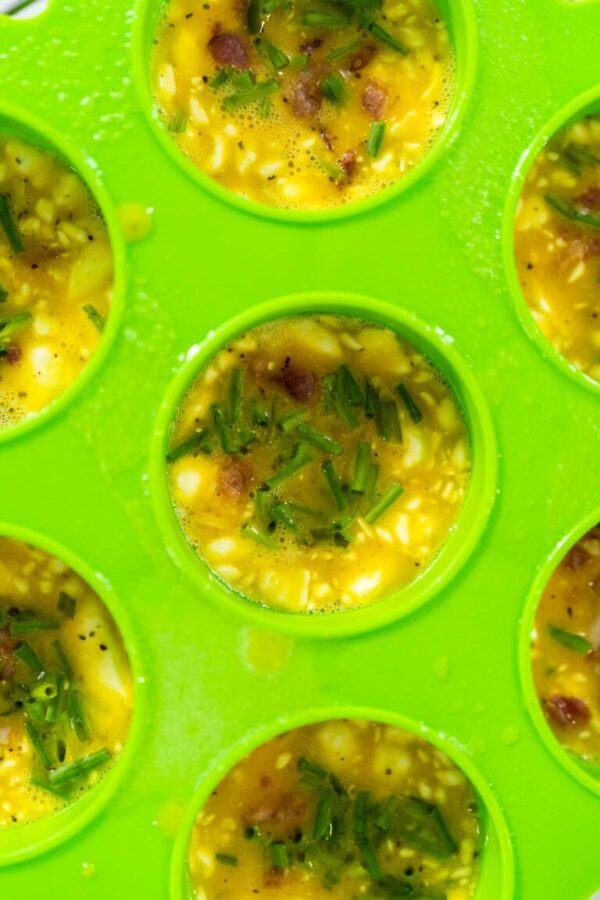 Filling silicone molds with egg mixture to make egg bites in a pressure cooker.