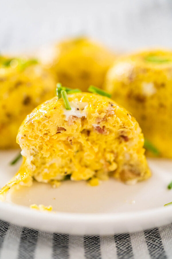 Serving egg bites garnished with fresh chives on a white plate.