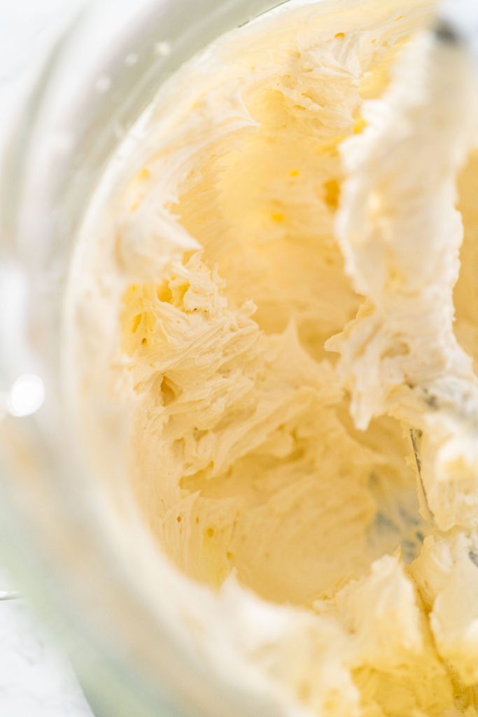 Lemon buttercream frosting whipped in a glass bowl until creamy.