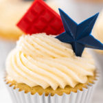 Frosted cupcake with red chocolate square and blue chocolate star topper.